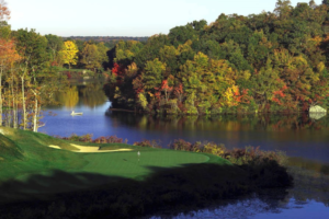Lake of Isles Golf Course greens as they meet a body of water. Across the water, trees changing colors.