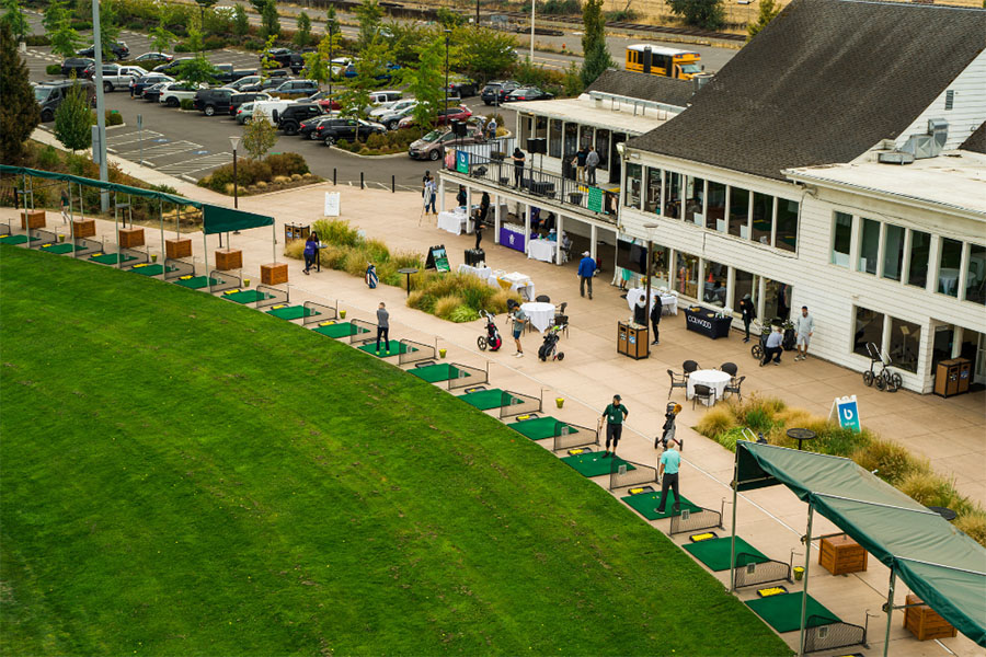 Overview of a golf driving range setting up for an event with booths.