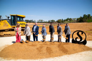 Group of KemperSports employees digging up a pile of dirt at the Saraland Groundbreaking ceremony.