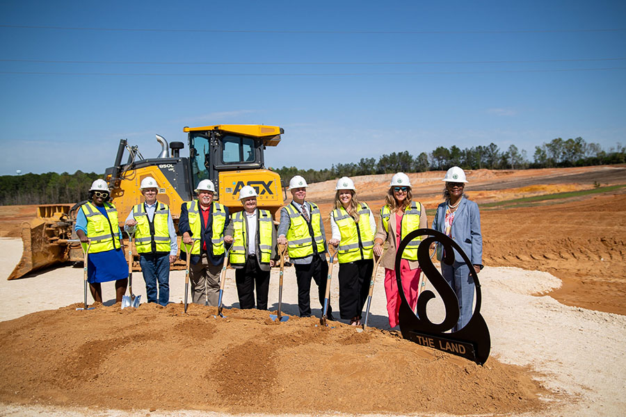 Group of KemperSports employees digging up a pile of dirt at the Saraland Groundbreaking ceremony.