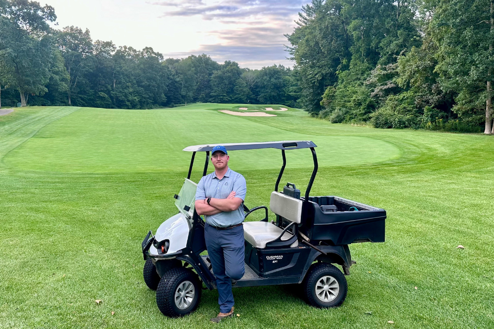 Lake of Isles Director of Agronomy Cody Woods poses against a golf cart on the course.